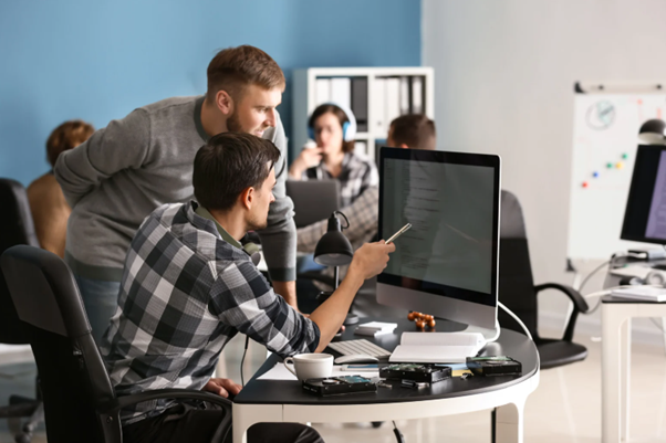 IT professionals collaborating at a computer demonstrating outsourced IT support services and technical problem solving in an office. 